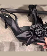 Stilvolle schwarze Sandalen mit Blumenmuster und hohem Absatz und spitzer Zehenpartie